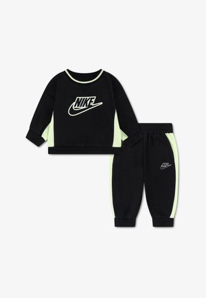 Svart Nike treningdress med logo på forsiden. Fremhevet med neongrønne striper langs ermene og buksene. Mykt stoff, avslappet passform.