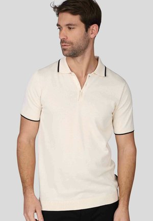Polo-shirt crème à manches courtes avec un col noir et des détails aux poignets. Fabriqué en tissu lisse avec une coupe ajustée et un motif subtil.