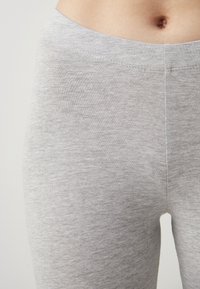 Light gray leggings made of soft, stretchy fabric with a smooth texture. Features a wide waistband and subtle ribbed pattern.