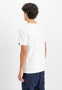 Tricou alb din bumbac cu mâneci scurte, guler rotund și un detaliu mic cu logo pe mâneca stângă. Textură netedă și croială normală.