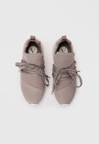 Graue Sportschuhe mit einem Obermaterial aus Mesh und glattem Material, das ein mehrschichtiges Design und auffällige Schnürsenkel aufweist. Weiße Gummisohle.