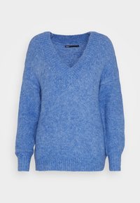 Mjuk, långärmad blå stickad tröja med djup V-ringning och ribbade muddar och fåll, uppvisad mot en enkel ljus bakgrund.