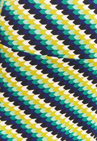 Kangas dengan pola geometris yang menampilkan bentuk zigzag dalam nuansa teal, kuning, hitam, dan putih dengan tekstur yang halus.