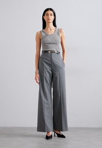 Gray ribbed tank top, high-waisted gray wide-leg trousers with front pleats, black belt with a gold buckle, paired with black high heels.
