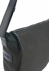 Borsa a tracolla nera con motivo tessurizzato a scaglie, tracolla in pelle e chiusura con zip. Il patch con logo laterale arricchisce il design elegante.