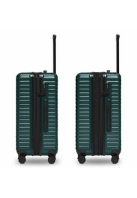 Harde koffer in donkergroen, met een geribbelde design, zwarte rits, telescopische handgreep en vier zwarte wielen voor gemakkelijke verplaatsing.