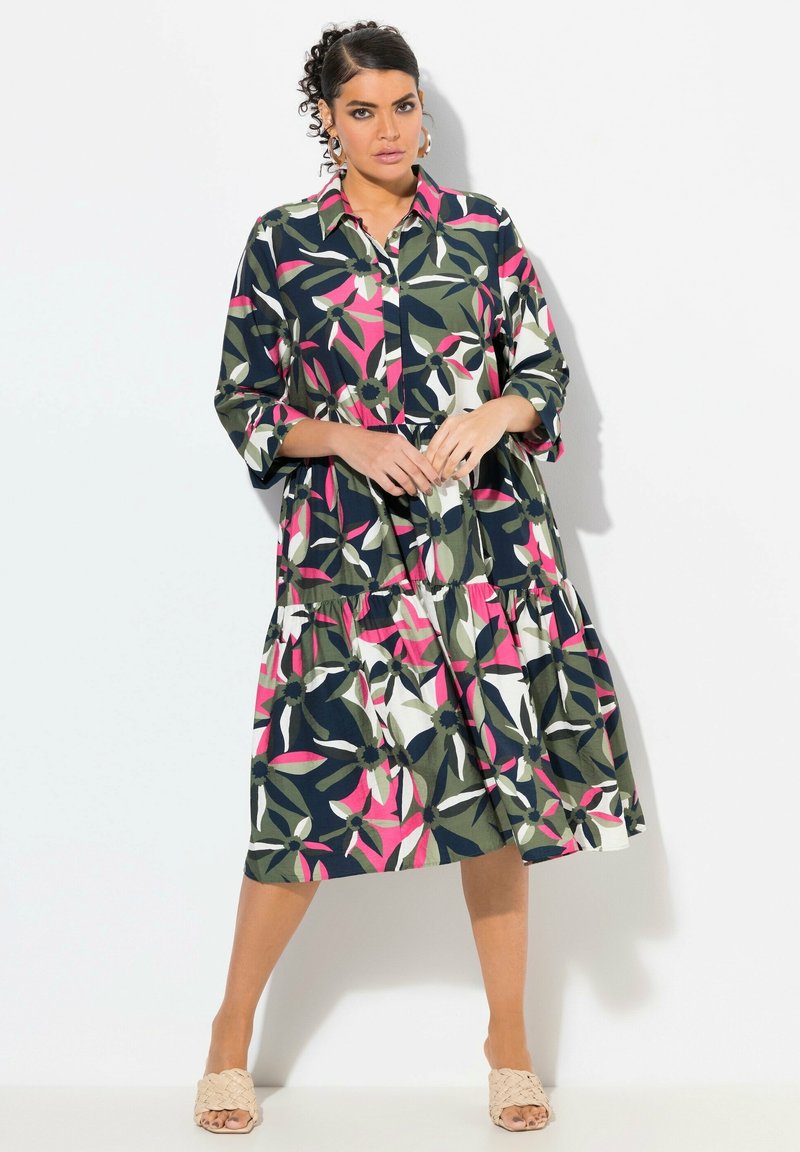 Krage maxi klänning i mörkgrön med blommönster som har rosa, vit och marinblå detaljer, lagerdesign och trekvartsärmar.