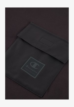 Felpa Champion nera con tasca con chiusura a ribaltina, texture liscia e logo prominente in un quadrato al centro.