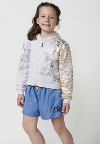 Svijetlo siva jakna na zip s cvjetnim i leopard rimovanjima, s plavim patentnim zatvaračem i detaljima od šarenih perlica. Uparena s plavim traper kratkim hlačama.