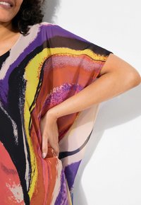 Top fluido e leggero dai motivi astratti multicolori, caratterizzato da tonalità audaci di viola, arancione e nero, con maniche ampie e una vestibilità rilassata.