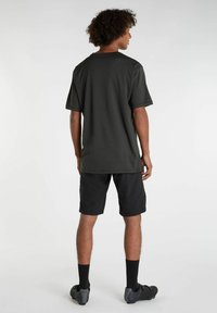 Tummanharmaa lyhythihainen paita, jossa on pyöreä kaula-aukko, yhdistettynä mustiin shortseihin. Asusteessa on sileä rakenne ja rento istuvuus.