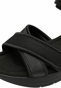 Sandale noire avec deux larges sangles en tissu et une semelle intérieure rembourrée. Elle présente une semelle texturée et des accents en matériau synthétique lisse.