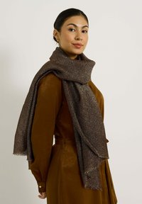 Écharpe marron en matériau texturé, avec des fils métalliques et des bords effilochés, enroulée de manière élégante autour du cou.