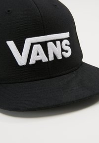 Cappello nero con visiera rigida, con il prominente logo "VANS" ricamato in bianco sulla parte anteriore. Realizzato in tessuto con texture.