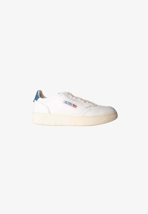 Sneaker bianca bassa con suola beige, linguetta posteriore blu, lacci e una piccola patch con la bandiera americana sul lato.