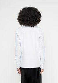 Svetlomodrá pruhovaná košeľa s dlhým rukávom, rovný zadný dizajn a manžety so zapínaním na gombíky, vyrobená z hladkej, mäkkej tkaniny.