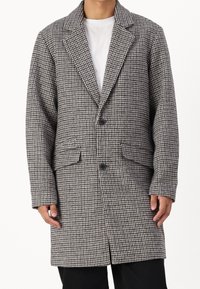 Abrigo con patrón pata de gallo en gris y negro, con cuello con solapa, dos bolsillos frontales y cierre de un solo botón. Material de mezcla de algodón.