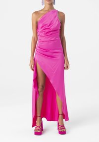 Robe rose à une épaule avec tissu froncé, fente haute et ourlet asymétrique. Associée à des sandales à plateforme roses à brides.