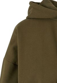 Gros plan d'un sweat à capuche vert olive montrant la texture du tissu et l'arrière de la capuche.