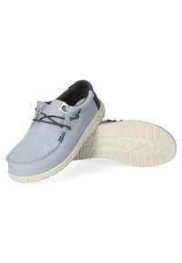 Scarpe in tela blu con una superficie testurizzata e suole in gomma di colore chiaro. Presentano lacci elasticizzati e accenti scuri a contrasto sul tallone.