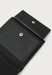 Portefeuille en cuir noir avec une texture lisse, doté d'une fermeture à pression et d'un compartiment pour cartes. Design simple avec des lignes nettes.