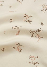 Cotton fabric in cream with a subtle texture, featuring small brown and pink floral patterns and delicate leaf accents throughout.