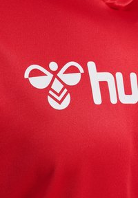 Czerwony materiał z białym logo stylizowanego ula nad słowem "hub". Projekt jest prosty, o gładkiej, matowej fakturze.