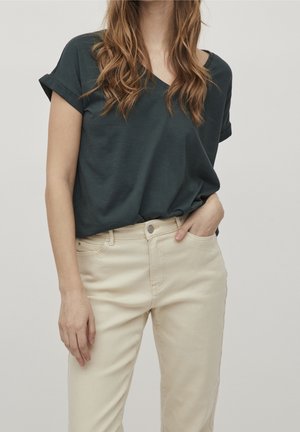 T-shirt vert foncé à col en V avec manches retroussées, associé à un pantalon beige clair. Le tissu semble doux avec une coupe décontractée.