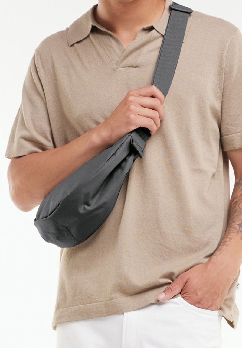 Sac bandoulière gris et profilé en tissu doux, doté d'une sangle réglable et d'une forme arrondie pour une meilleure facilité de port.
