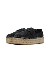 Scarpe slip-on nere in tessuto intrecciato con tomaia testurizzata, dotate di una suola in piattaforma di juta e suola in gomma, che conferiscono un design casual.