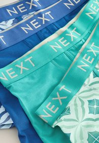 Quatre paires de boxers pour hommes, comprenant des tissus bleu, bleu-vert et à motifs, avec des ceintures élastiques portant la mention "NEXT" dans des couleurs contrastées.