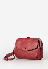 Borsa a tracolla in pelle rossa con chiusura a pattina, caratterizzata da un design arrotondato, superficie testurizzata e dettagli in metallo nero nella parte superiore.