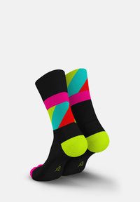 Bunte Socken mit schwarzem Grund und geometrischen Mustern in lebendigen Farben: Neonpink, Grün, Blau und Rot. Kontrastierende Zehen- und Fersenakzente.