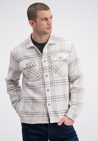 Geruit overhemd in wit, grijs en oranje. Voorzien van borstzakken met knopen, een kraag, gestructureerde stof en een ontspannen pasvorm.