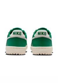 Zielone skórzane sneakersy z białymi akcentami, z teksturowaną gumową podeszwą i wyraźnym logo "NIKE" na pięcie.