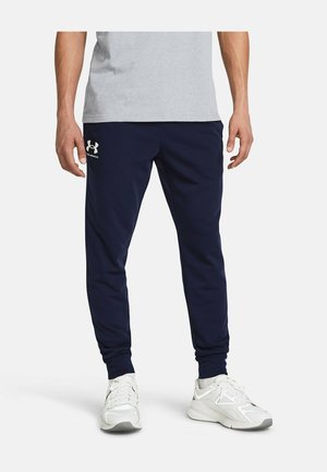 Maritieme trainingsbroek gemaakt van een zachte stof; heeft een gecuffte zoom en een klein logo-accent op het linkerbeen. Gepaard met lichte sneakers.