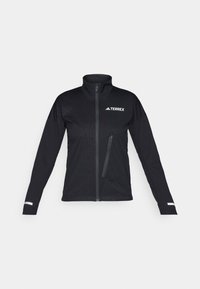 Svart softshell-jakke med høy krage, glidelås foran, sidelomme, strukturert mønster på stoffet og reflekterende detaljer på ermene.