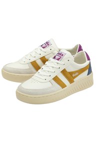 Sneakers bianchi con punta in suede, strisce marroni e arancioni, e un accento viola sul tallone. Costruzione in pelle testurizzata.