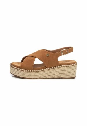 Sandalias de cuña de ante marrón con diseño de tiras cruzadas, correa de tobillo ajustable y suela de yute texturizada. Presenta un detalle del logotipo dorado.