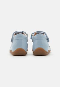 Light blue patent leather shoes with rounded backs, Velcro straps, and tan rubber soles. Smooth texture with minimal detailing.