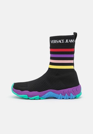 Versace Jeans black sock-style sneaker with colorful striped band, purple and teal rubber sole, textured upper, and logo on ankle.