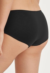 Schwarze Baumwoll-Shorts für Jungen mit einem glatten, elastischen Bund und einem taillierten Design, das einen einfachen, nahtlosen Schnitt und minimale Details zeigt.