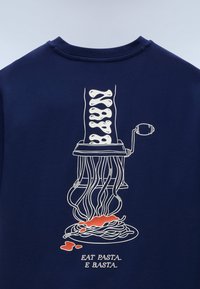 Μπλε πουκάμισο με λευκό σχέδιο που απεικονίζει μηχανή ζυμαρικών να βγάζει σπαγγέτι με κόκκινη σάλτσα και κείμενο «ΦΑΕ ΖΥΜΑΡΙΚΑ. ΤΕΛΟΣ.»