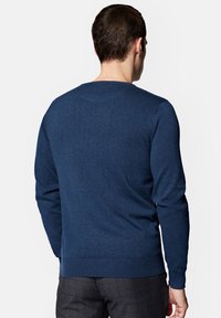 Granatowy sweter dzianinowy z okrągłym dekoltem oraz ściągaczami u rękawów i u dołu, charakteryzujący się gładką fakturą i dopasowanym krojem.