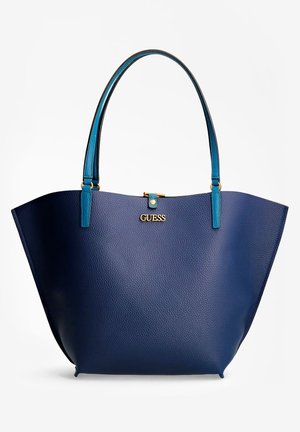Blauwe lederen tas met structuur, turquoise handvatten en een gouden "GUESS"-logo centraal geplaatst nabij de bovenkant.