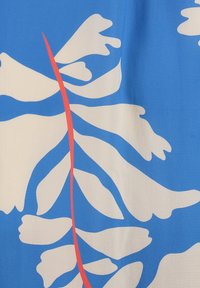 Blauer Stoff mit weißen blattartigen Formen und einer zentralen roten Akzentlinie, mit glatter Textur und gewagtem Grafikdesign.