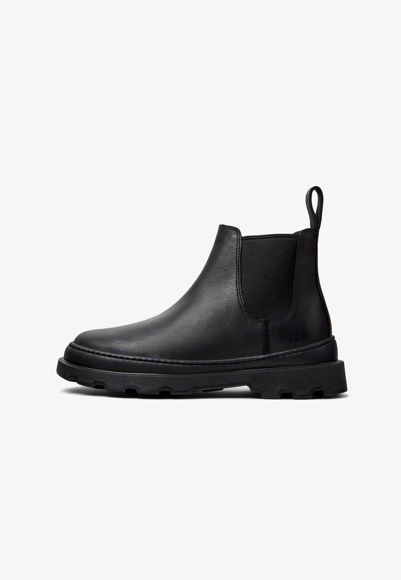 Bottine Chelsea en cuir noir avec panneau latéral élastique, languette au talon et semelle épaisse et robuste, vue de profil sur fond blanc.