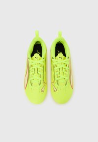 Scarpe sportive con tomaia sintetica giallo brillante, interno nero, linee di accento rosse e un logo Puma ben visibile sul lato.