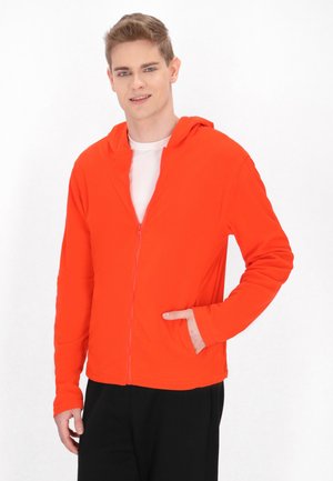 Hooded zip-up jas in feloranje, met lange mouwen, zakken en een gladde, zachte textuur. Gekoeld met zwarte broeken.