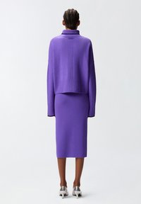 Maglione lavorato a maglia viola con colletto alto e polsini a coste, abbinato a una gonna a tubo aderente dello stesso colore, in tessuto a maglia testurizzato.
